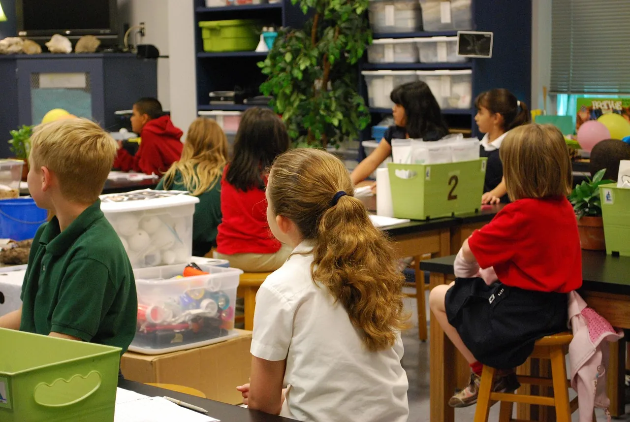 A primary classroom of uniformed students seated and working at their tables